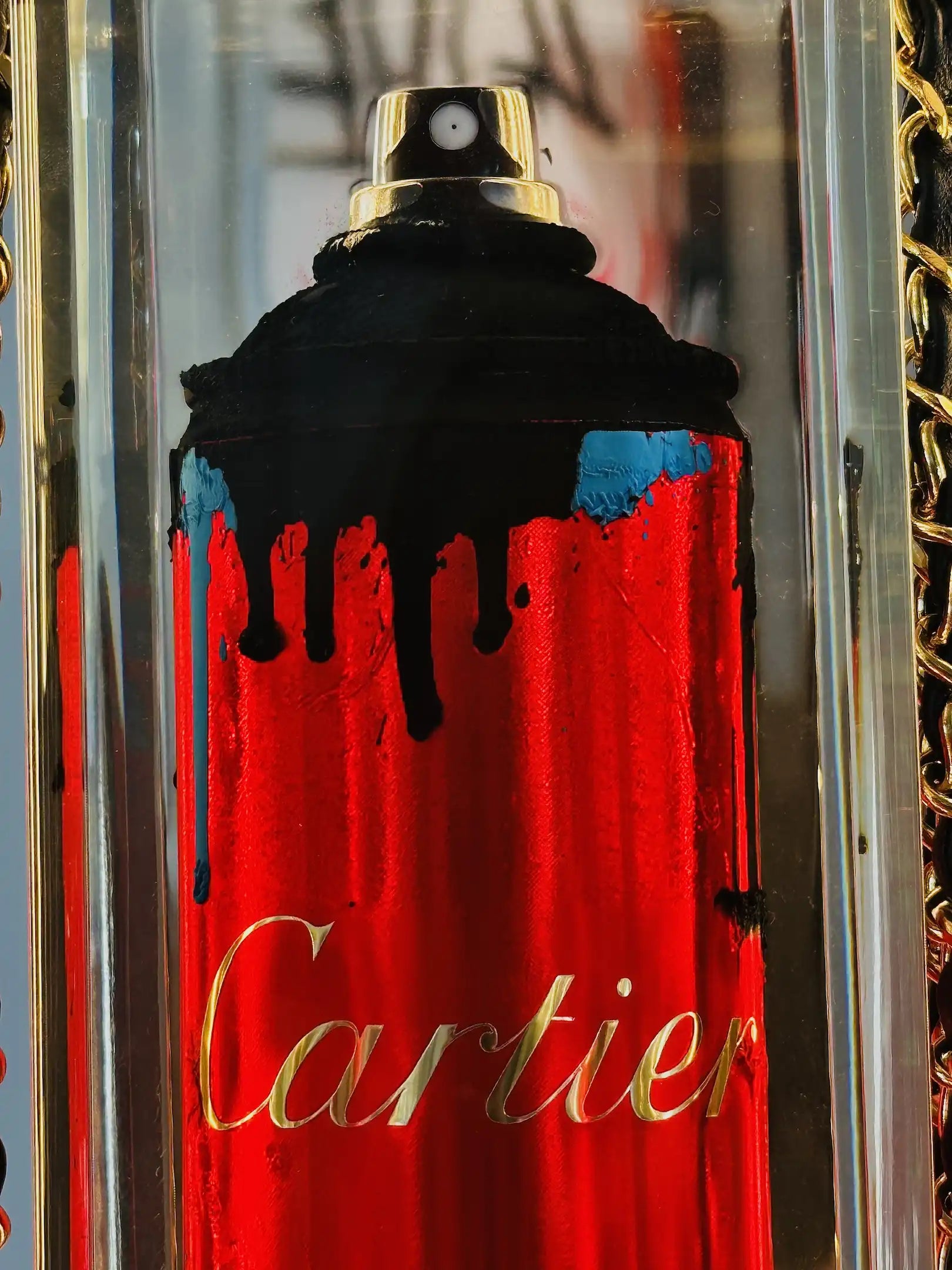 Une bombe de peinture rouge portant l'inscription "Cartier" en lettres d'or, recouverte de gouttes noires, évoque une minaudière Cartier. "Undercover" de Fred Allard est présenté dans un boîtier transparent avec une chaîne en or.